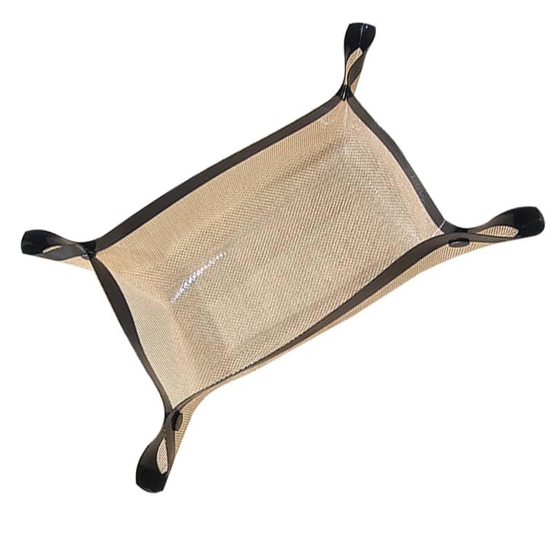 A beige silicone baking mat with black raised edges, folded up at the corners to create a tray or basket-like shape, shown on a white background.